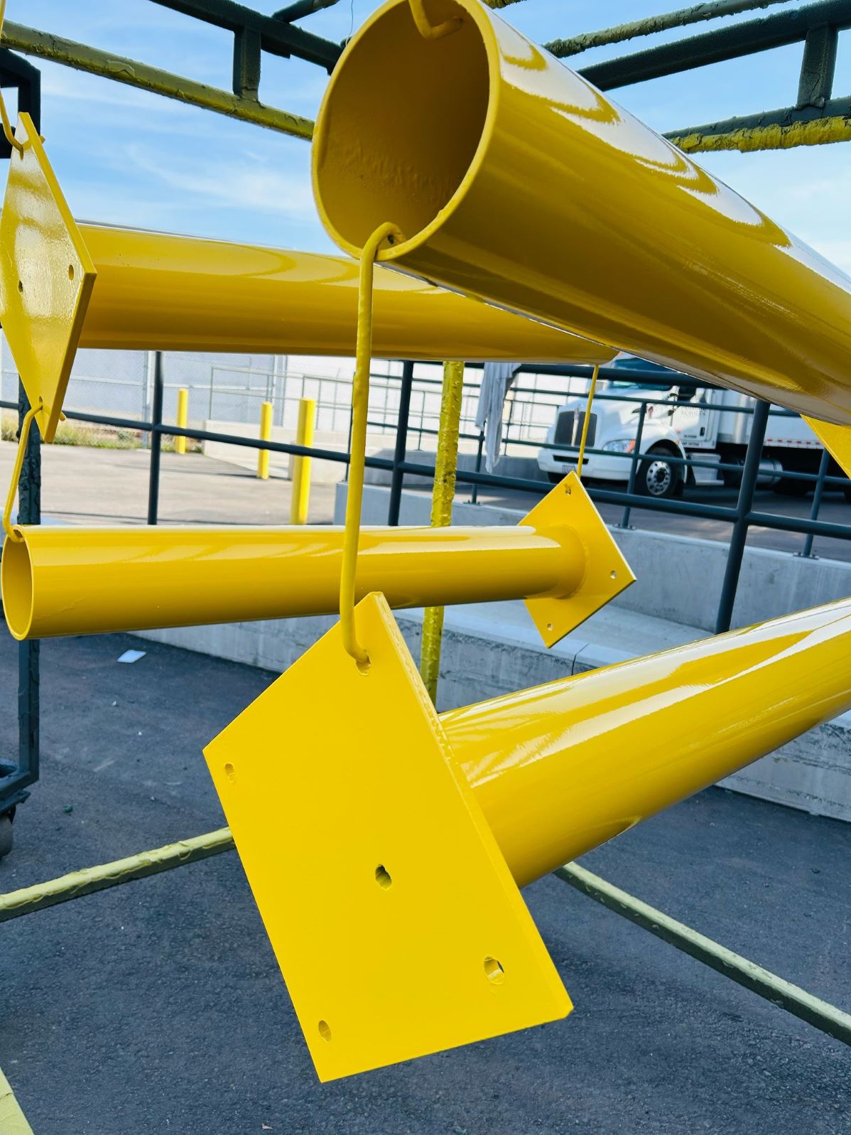 Yellow powder coated steel poles hanging to cure