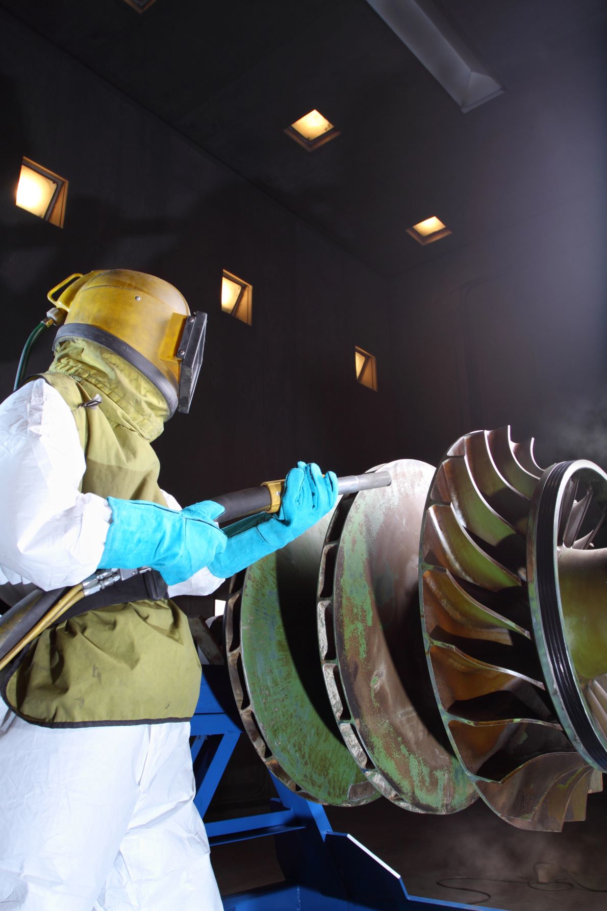 Sandblasting a turbine part in a blast booth