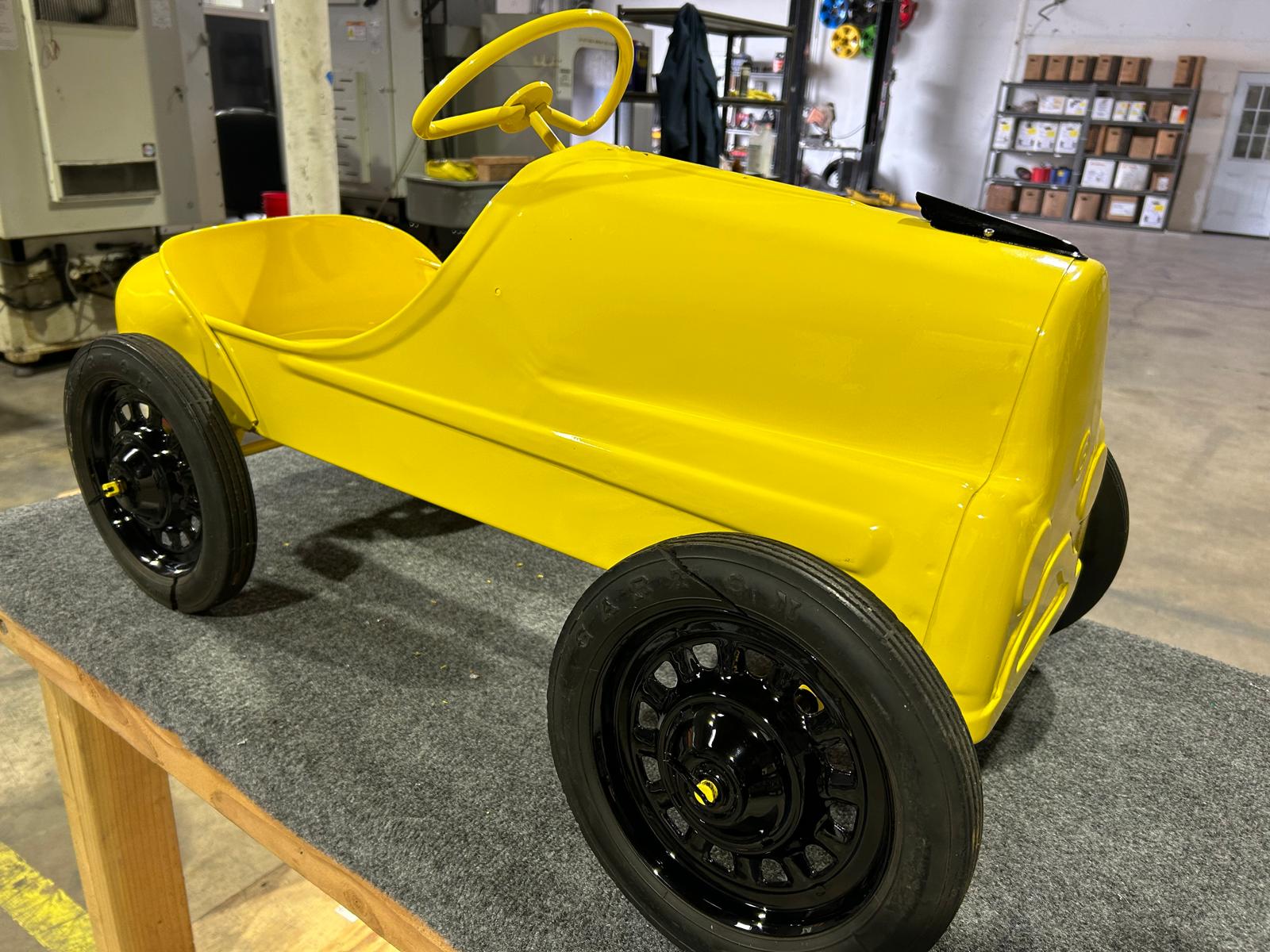 Yellow powder coated pedal car in the shop