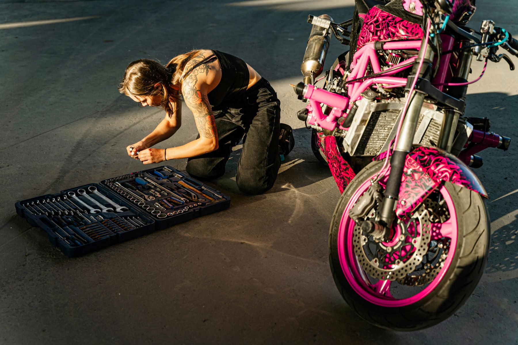 Mechanic working on a pink powder coated custom motorcycle