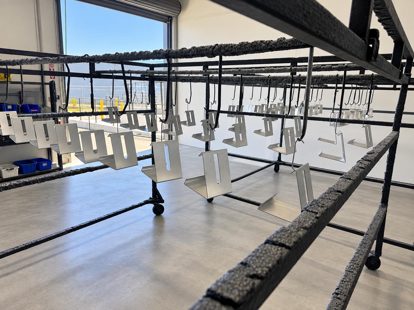 Racked metal parts loaded for a batch powder coating production run